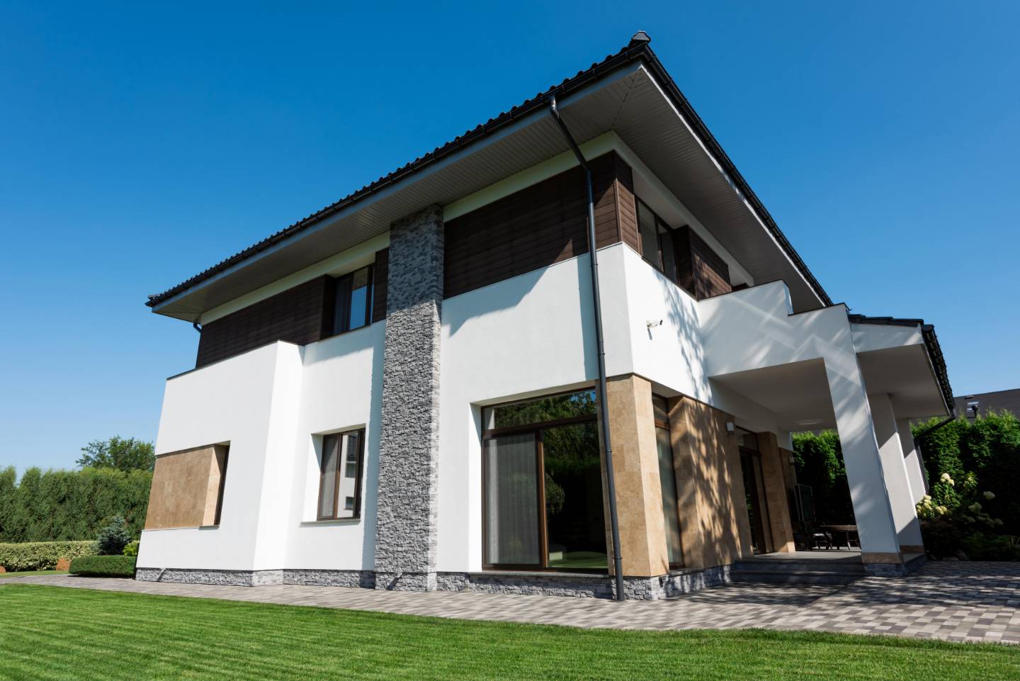 Modernes zweistöckiges Haus mit weißen Wänden, großen Fenstern und einem gepflegten grünen Rasen unter freiem Himmel - ideal für Immobilien in Deutschland mit solider Finanzplanung.